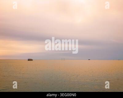 Eine friedliche Küstenszene bei Sonnenaufgang oder Sonnenuntergang, mit weichen Pastelltönen in Rosa, Pfirsich und Lavendel, die sich über den Himmel erstrecken. Stockfoto
