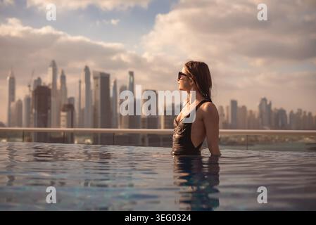 Frau genießt Infinity Pool mit Blick auf die Skyline von dubai Stockfoto