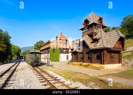 Historische hölzerne Bahnhofsgebäude und ein klassischer Zug auf der Sargan 8 Eisenbahn in Mokra Gora, Serbien Stockfoto