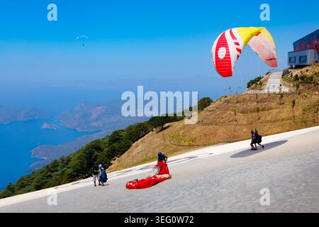 Oludeniz, Türkei - 12. Juli 2022: Fliegender Gleitschirmflieger auf dem Gipfel des Babadag im Bezirk Fethiye der Provinz Mugla, Türkei. Stockfoto