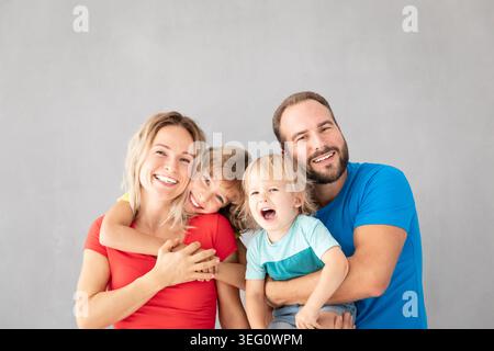 Porträt glücklicher Familie - Vater, Mutter, Tochter und Sohn - vor grauem Hintergrund. Eltern mit Kindern, die zu Hause Spaß haben. Stockfoto