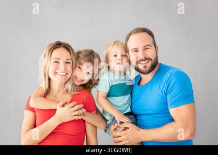 Porträt glücklicher Familie - Vater, Mutter, Tochter und Sohn - vor grauem Hintergrund. Eltern mit Kindern, die zu Hause Spaß haben. Stockfoto