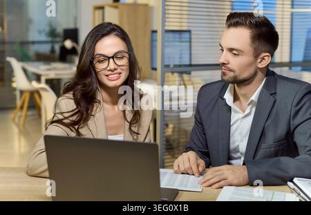 Geschäftsmann und Geschäftsfrau prüfen Finanzdaten auf Laptop während eines Bürogesprächs Stockfoto