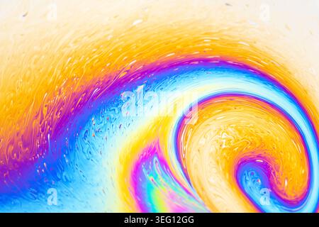 Makroansicht von irisierenden Farben und fließenden Mustern auf einer Seifenblasenfolie, die Interferenzfarben und Lichtbrechung zeigt Stockfoto