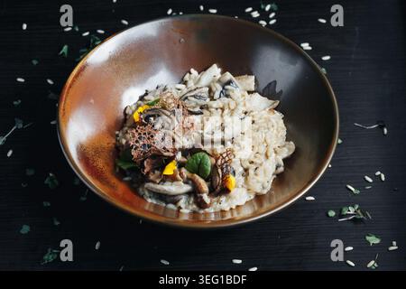 Herzhaftes Pilzrisotto garniert mit Kräutern und Sesamsamen Stockfoto