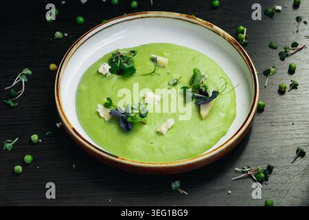 Leuchtend grüne Erbsensuppe auf dunkler Oberfläche, für Gourmet-Fotos Stockfoto