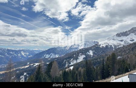 Panoramablick auf die schneebedeckten Berggipfel der Dolomiten unter einem dramatisch bewölkten blauen Himmel. Malerische alpine Landschaft im Val di Fassa, Trentino, Italien. Stockfoto
