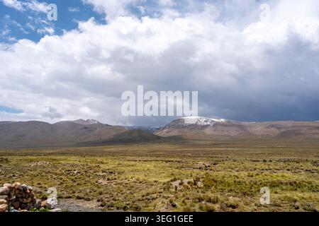 Ein riesiges, trockenes Tal unter einem dramatischen Himmel in Peru, das die natürliche Schönheit der Wüste und die umliegenden Berge zeigt. Stockfoto