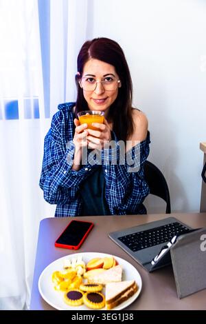 Frau genießt morgendliche Routine, während sie ferngesteuert arbeitet Stockfoto