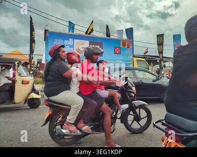 Eine Familie mit zwei Eltern und zwei Kindern, die im starken Verkehr am Galle International Cricket Stadium in Sri Lanka vorbeifahren Stockfoto