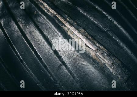 Ein dunkelblauer, umgedrehter Fiberglas-Rumpf eines kleinen Bootes am Stackpole Quay. Beide Seiten des beschädigten Metallkiels sind gekrümmte, parallele Linien. Stockfoto