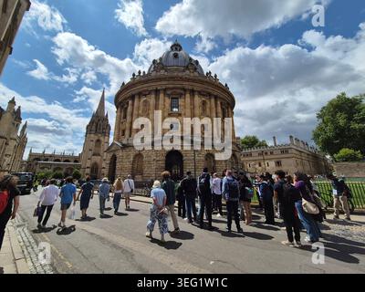 Alte historische Gebäude in einer Straße in Oxford, England. Leute, die um das Radcliffe Camera Gebäude am Radcliffe Square laufen Stockfoto
