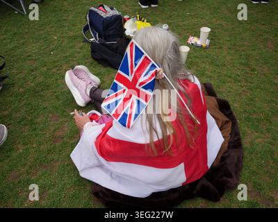 London, Großbritannien. 16. Mai 2026. Eine Demonstrantin, die eine Union Jack-Flagge in den Haaren trägt, macht eine Zigarettenpause vor den Houses of Parliament auf dem Parliament Square, während sie Reden während der von dem rechtsextremen Politiker Tommy Robinson (Stephen Yaxley-Lennon) organisierten Kundgebung „Unite the Kingdom“ hört. Die Anhänger schwenkten die Flaggen der Union Jacks und des St. George’s Cross und forderten strengere Einwanderungskontrollen. Die Metropolitan Police führte eine große Sicherheitsoperation in Westminster durch, um die Kundgebung von gleichzeitigen Nakba Day Pro-Palästina- und antifaschistischen Gegendemonstrationen zu trennen Stockfoto