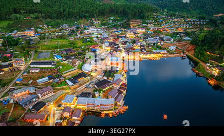 Baan Rak Thai Village bei Sonnenuntergang Reflektionen von Häusern und Restaurants entlang des Sees in chinesischer Architektur mit bunten Lichtern säumen das Wasser Stockfoto