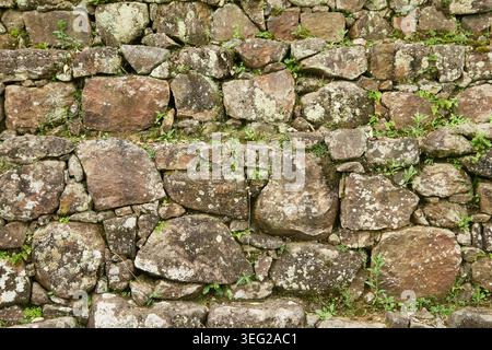 Alte Trockensteinmauer aus Felsen, unregelmäßiges Mauerwerk mit grauen und braunen Mustern, Vollrahmen-Hintergrundstruktur Stockfoto