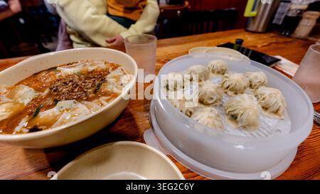 Eine lebendige Show traditioneller koreanischer Küche mit einer köstlichen Auswahl an Knödeln und scharfen, gehackten Nudeln in einem gemütlichen Seoul Restaurant Stockfoto