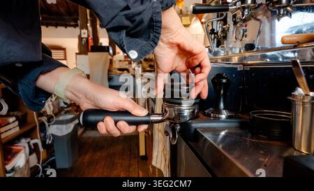 Ein Barista bereitet in einem gemütlichen südkoreanischen Café einen Espresso fachmännisch zu. Die Hände konzentrieren sich auf eine Espressomaschine und zeigen die Kunst der Kaffeezubereitung Stockfoto