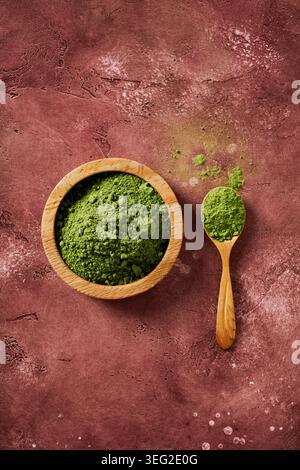 Blick von oben auf zeremonielles Matcha-Pulver in einer Holzschale und Löffel auf rustikalem Hintergrund. Minimales Zen Wabi-Sabi-Ästhetik für Superfood, Tee, Wellne Stockfoto