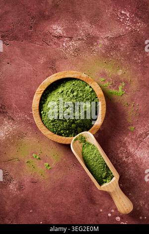 Blick von oben auf zeremonielles Matcha-Pulver in einer Holzschale und Schaufel auf rustikalem Hintergrund, das an Zen Wabi-Sabi-Ästhetik erinnert, Superfood-Teezutat Stockfoto