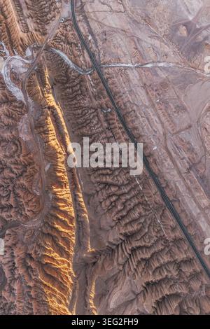 Aus der Höhe aus der Vogelperspektive der malerischen Straßen, die sich durch die Atacama-Wüste in Chile ziehen, mit zerklüfteten Graten, trockenen Tälern und sonnendurchfluteten Texturen, die eine dura bilden Stockfoto