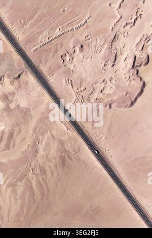 Drohnenblick auf eine lange, malerische Autobahn, die die Atacama-Wüste in Chile überquert, mit trockenen Sandstrukturen und zerklüfteten Felsformationen in einem abgelegenen, expansi Stockfoto