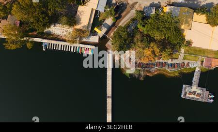 Blick auf das Resort aus der Vogelperspektive mit langem Pier, der den See überquert, und farbenfrohen Kajaks auf einem Dock Stockfoto