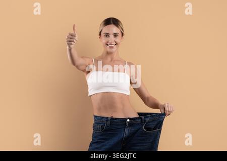 Schlanke junge Frau mit übergroßen Jeans nach erfolgreichem Gewichtsverlust Stockfoto