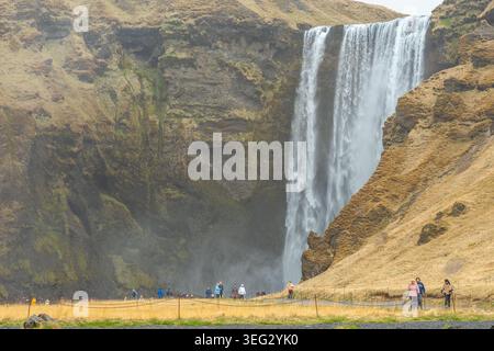 Touristen vor Skogafoss, einem wunderbaren Wasserfall am Skoga Fluss im Süden Islands an der Klippe, die die ehemalige Küste markiert Stockfoto