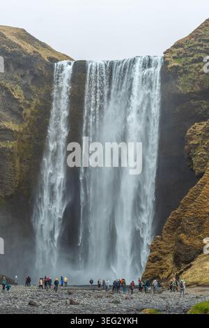 Touristen vor Skogafoss, einem wunderbaren Wasserfall am Skoga Fluss im Süden Islands an der Klippe, die die ehemalige Küste markiert Stockfoto