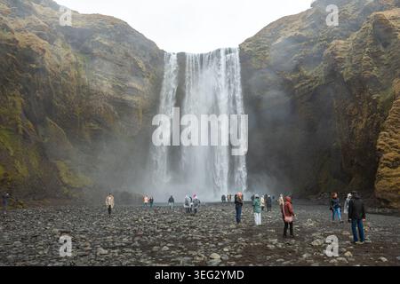 Touristen vor Skogafoss, einem wunderbaren Wasserfall am Skoga Fluss im Süden Islands an der Klippe, die die ehemalige Küste markiert Stockfoto