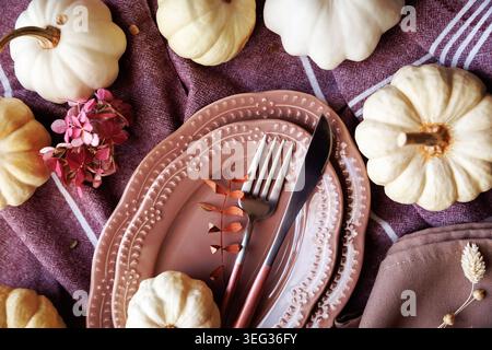 Festliches Thanksgiving-Tischset mit Kürbissen und rosafarbenem Teller Stockfoto
