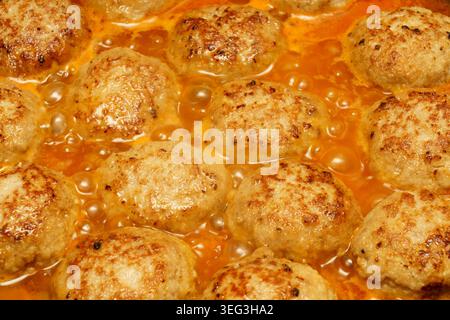 Fleischbällchen kochen in Soße auf dem Herd. Blasen bilden sich, wenn sie braun werden und in einem Topf köcheln. Stockfoto