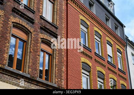 Beeindruckender Kontrast zwischen einem unrestaurierten, verwitterten Backsteinhaus und einer wunderschön restaurierten, leuchtenden roten und gelben Backsteinfassade nebenan Stockfoto