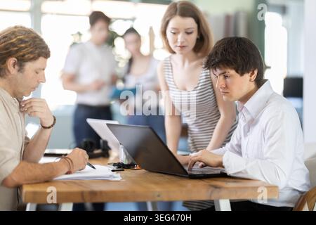 Mitarbeiter, die im Büro mit Laptops und Papierdokumenten arbeiten Stockfoto