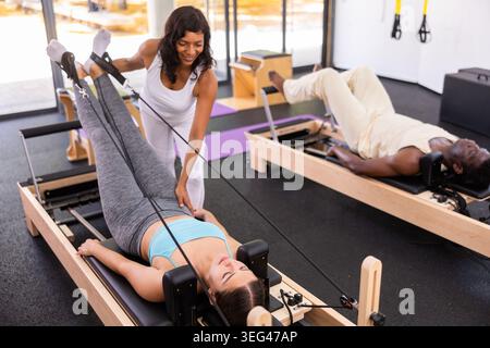 Aktive junge Frau und afroamerikanischer Mann, der Pilates-Übungen macht Stockfoto