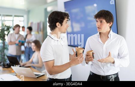 Kaffeepause - zwei Männer trinken Kaffee und unterhalten sich während der Pause im Büro Stockfoto