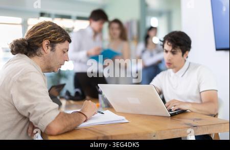 Mitarbeiter, die im Büro mit Laptops und Papierdokumenten arbeiten Stockfoto