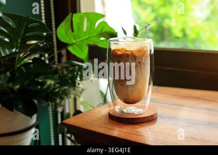 Milchkaffee serviert auf doppelwandigem Glas, auf Kaffeetisch Stockfoto