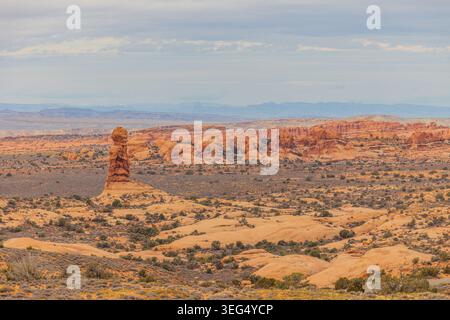 Rote Sandsteinfelder erheben sich gegen einen weichen, bewölkten Himmel in der riesigen Wüstenlandschaft des Monument Valley. Stockfoto