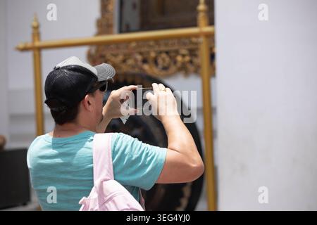 Männlicher Tourist in Cap fotografieren mit Smartphone, Touristen beobachten lokale religiöse Kultur, Rückansicht Stockfoto