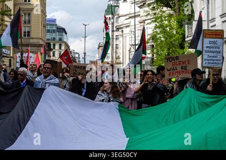 Die Demonstranten skandieren Slogans, während sie während der Demonstration Plakate hinter einer großen palästinensischen Flagge halten. Pro-palästinensische Aktivisten marschierten durch Warschau, um dem 78. Jahrestag der Nakba zu gedenken. Mit Fahnen und Plakaten marschieren Demonstranten von der Botschaft der Vereinigten Staaten von Amerika zur israelischen Botschaft und machen Halt an der örtlichen Bar Plan B, die eine pro-palästinensische Kunstmesse veranstaltete. Die Nakba, arabisch für „Katastrophe“, bezieht sich auf die Massenvertreibung und Enteignung von Hunderttausenden und die Ermordung von Zehntausenden Palästinensern während der arabisch-israelischen Wa 1948 Stockfoto