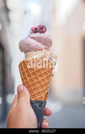 Hand mit einem Waffelkegel und zwei Schaufeln Eis an einem warmen Sommertag in Rom, Italien Stockfoto