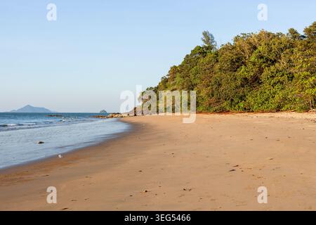 Andaman Coast Beach mit üppigem Grün und ruhigem Wasser. Sandstrand trifft auf dichten tropischen Wald unter klarem Himmel. Stockfoto
