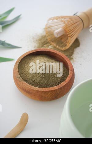 matcha-Pulver mit Schneebesen und Schüssel auf weißer Oberfläche Stockfoto
