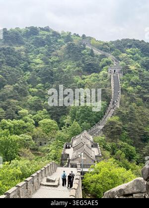 Die Chinesische Mauer von Mutianyu schlängelt sich über bewaldete Berge in der Nähe von Peking und zeigt historische Wachtürme, alte Steinarchitektur und malerische Landschaften. Stockfoto