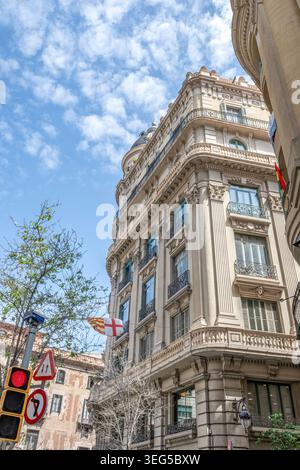 Historische neoklassizistische Gebäudefassade an der Via Laietana, elegant verzierte Balkone und Barcelona-Flagge, Barcelona, Spanien Stockfoto