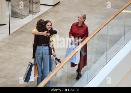 Erwachsene Frauen, die sich während eines Einkaufstages mit einer Seniorin umarmen Stockfoto