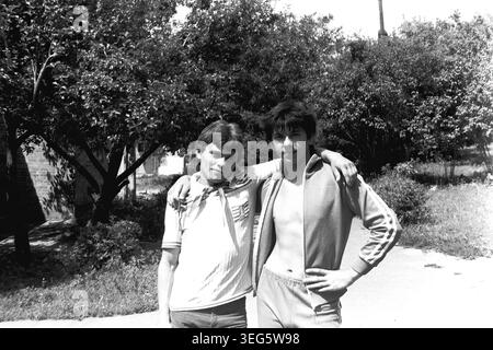 Slawjansk, Ukrainische SSR, 1983. Vintage-Schwarzweiß-Fotografie aus dem Pionierlager Vishegorsk in der Gegend von Slavkurort. Das Bild zeigt zwei junge männliche Lagermitarbeiter, die draußen zusammen stehen. Einer trägt eine Pionier-Krawatte, während Dmitri Michailowitsch Kravelis neben ihm steht und selbstbewusst für die Kamera posiert. Dieses authentische Archivbild fängt die Atmosphäre der sowjetischen Jugendkultur, des alltäglichen Lebensstils und der Sommererholung ein. Ein nostalgischer historischer Einblick in die Vergangenheit, der einen friedlichen Donbass darstellt. Stockfoto