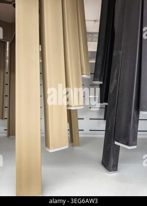 Eine Sammlung von gestapelten Möbelbeinen, einige in einem hellen beigen Farbton und andere in einem dunklen Schwarz, die ihr strukturelles Design und ihre Materialien zeigen Stockfoto