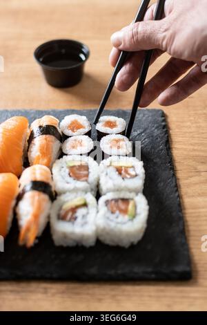 Frau isst Sushi mit Essstäbchen zu Hause Stockfoto